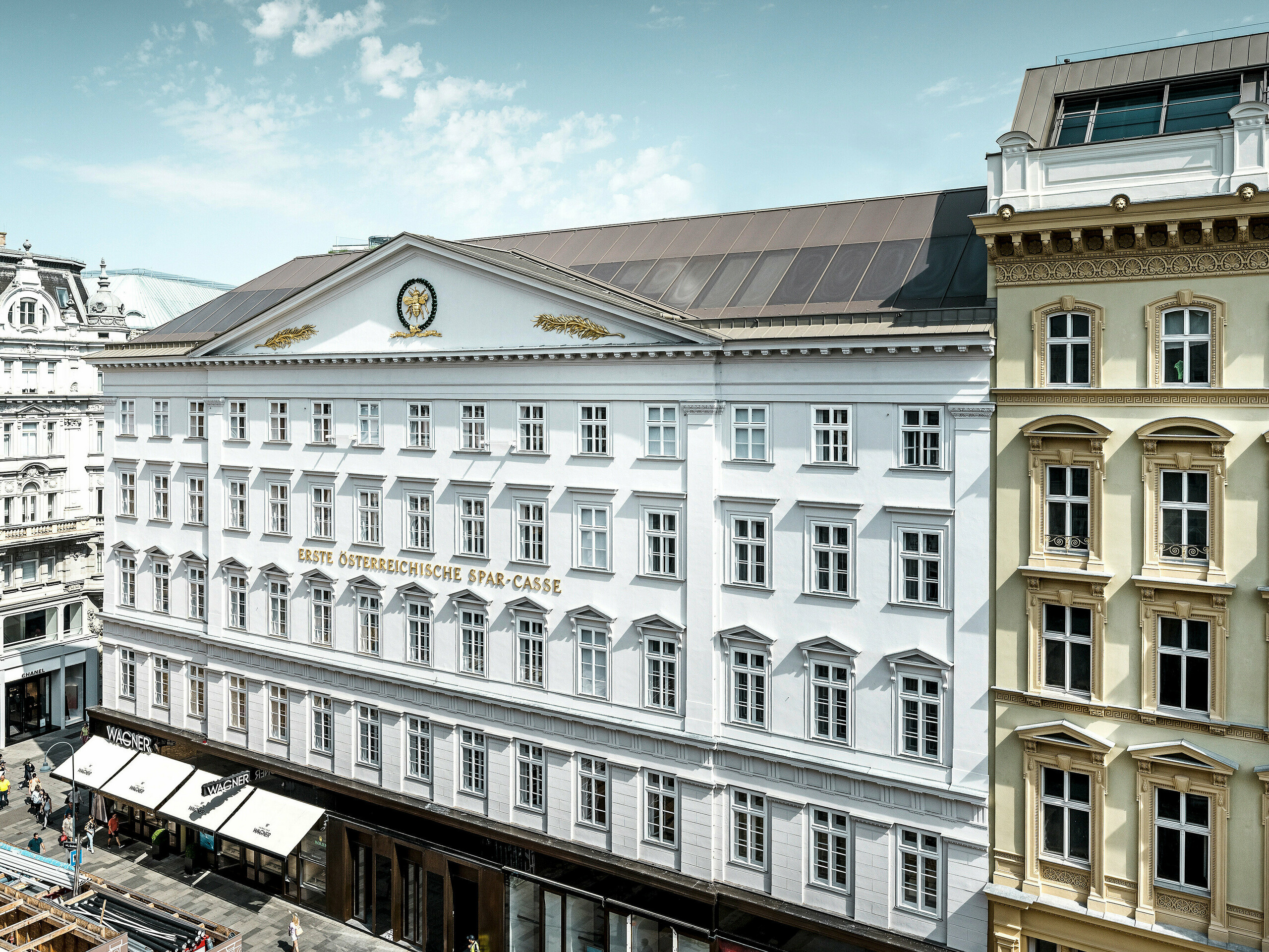 Seitliche Frontansicht des Hotels mit der historischen Fassade und dem bronzenen Aluminiumdach.