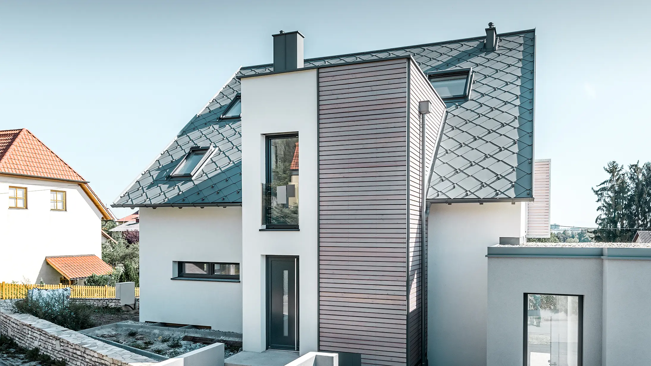 La casa unifamiliare con tetto a due falde a Leonding è stata completamente ristrutturata. La superficie del tetto è stata rivestita con scaglia 44 x 44 PREFA in grigio chiaro, compresi i nasi paraneve. La grondaia è la semicircolare di PREFA, anch’essa in grigio chiaro. 