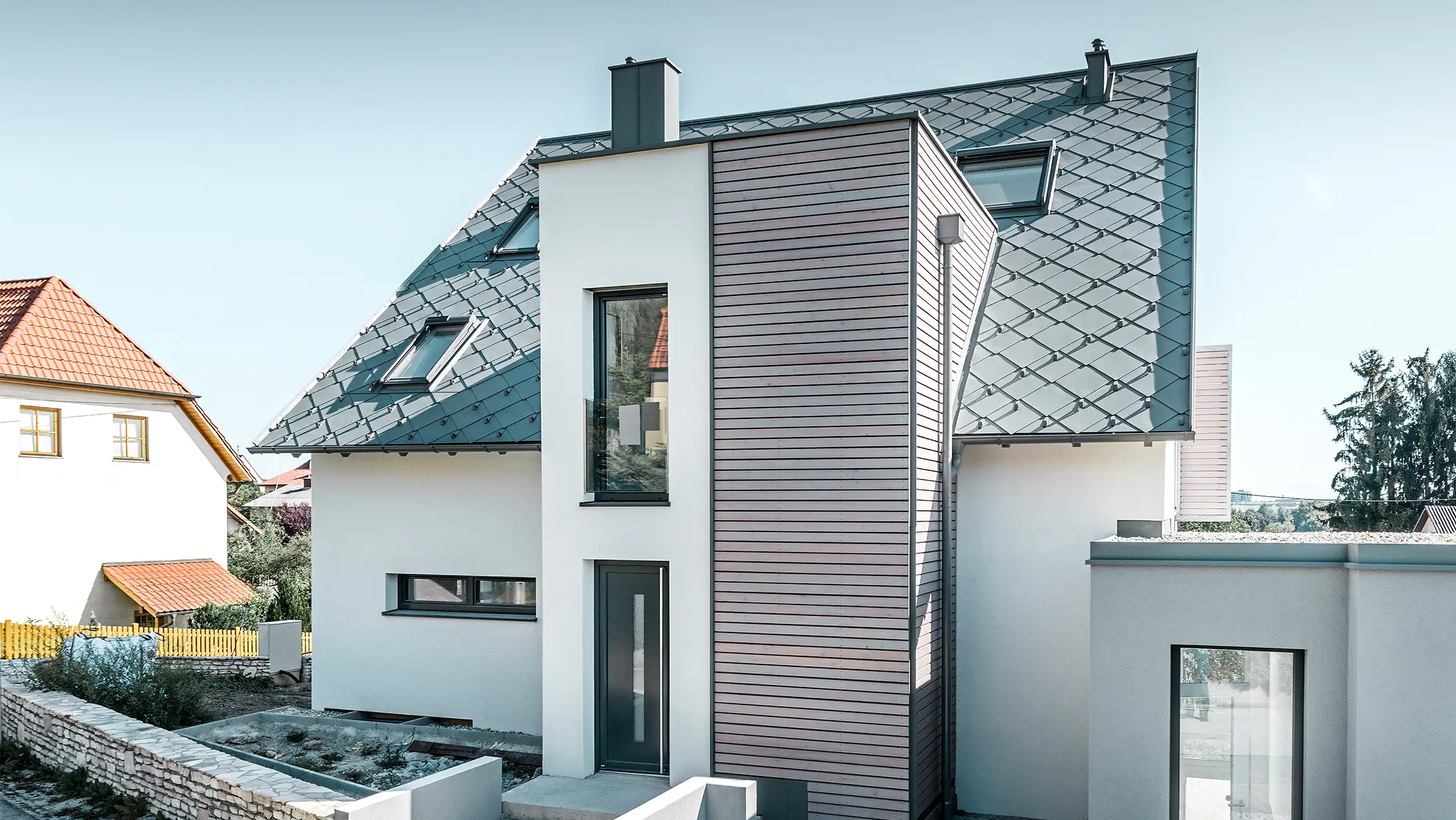 La maison individuelle avec toit à deux pans à Leonding a été entièrement rénovée. La surface de toit a été recouverte de losanges de toiture 44 × 44 PREFA couleur gris souris avec arrêts neige. Le choix s’est porté sur la gouttière suspendue de PREFA, également couleur gris souris. 