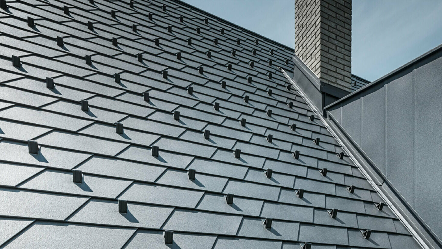 Toit rénové à l'aide de bardeaux de toiture PREFA dans la couleur P.10 noir avec arrêts de neige, lucarne revêtue d'aluminium PREFA