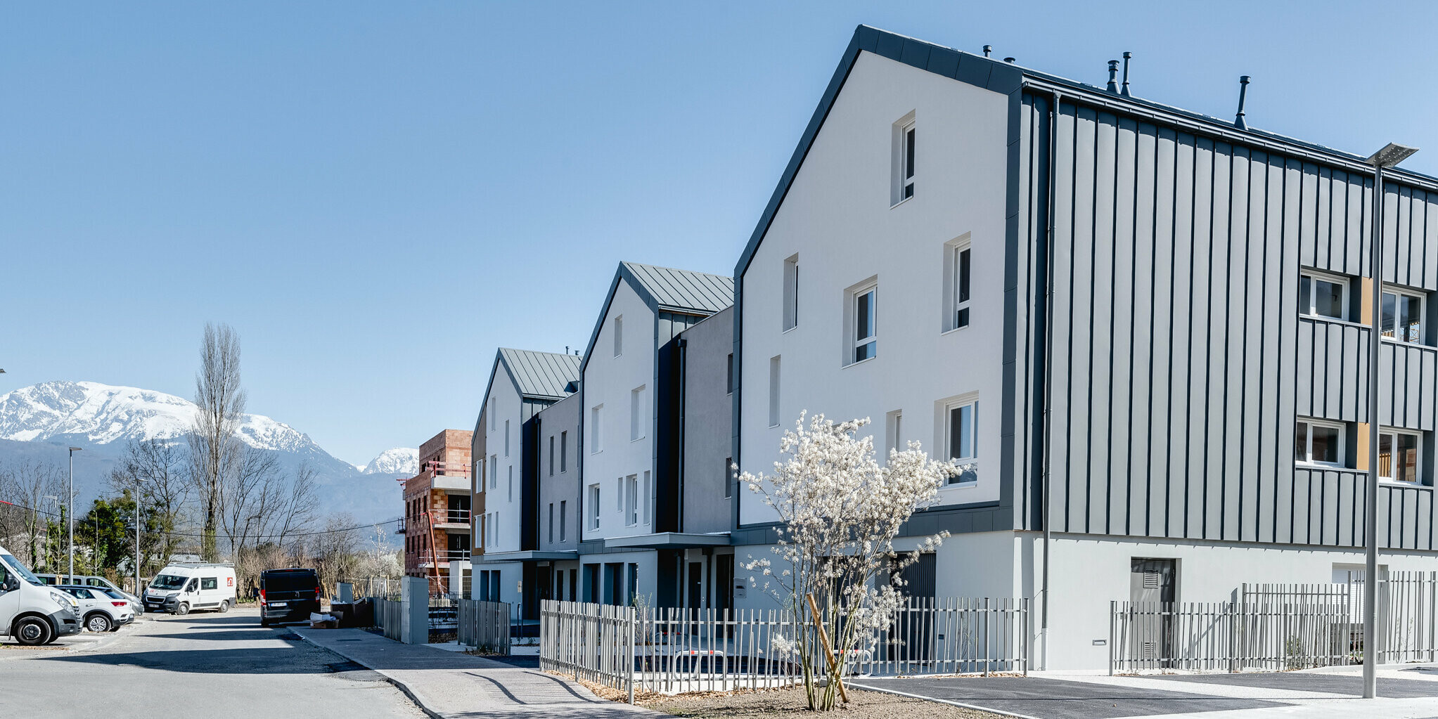 La Résidence L'Athéna se compose de plusieurs parties du bâtiment qui ont été revêtues de PREFALZ en P.10 gris souris. Le complexe résidentiel a été construit par ARCANE Architectes à Varces-Allières-et-Risset, France.