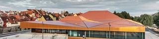 Deutsche Veranstaltungshalle mit PREFA Falzonal an Dach und Fassade in einer Sonderfarbe, ähnlich neukupfer