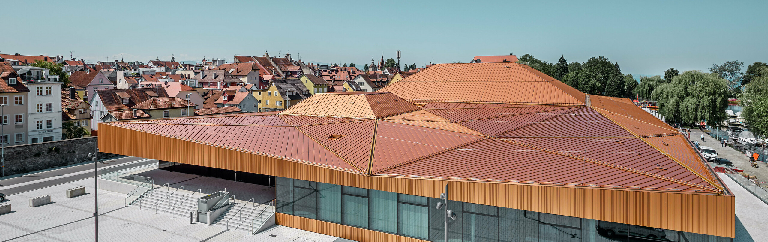 Inselhalle in Lindau mit Falzonal von PREFA – Auer Weber Architekten Deutsche Veranstaltungshalle mit PREFA Falzonal an Dach und Fassade in einer Sonderfarbe, ähnlich neukupfer