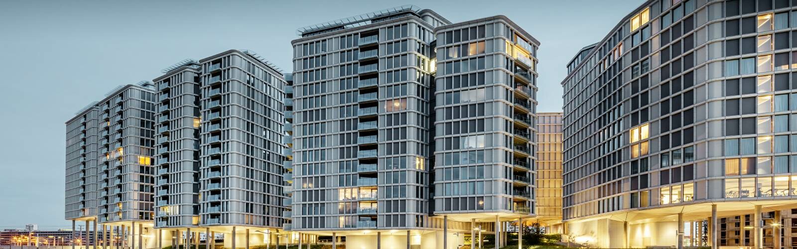 [Translate to français:] Vorderansicht der Belvedere Apartments am Abend. Die PREFA Profilwelle wurde mit Glas und Keramikelementen kombiniert