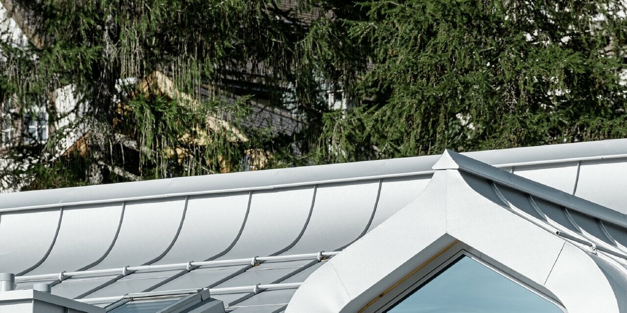 Complesso residenziale a St. Moritz con facciata in legno e copertura in alluminio con grondaia curva in silver metallizzato