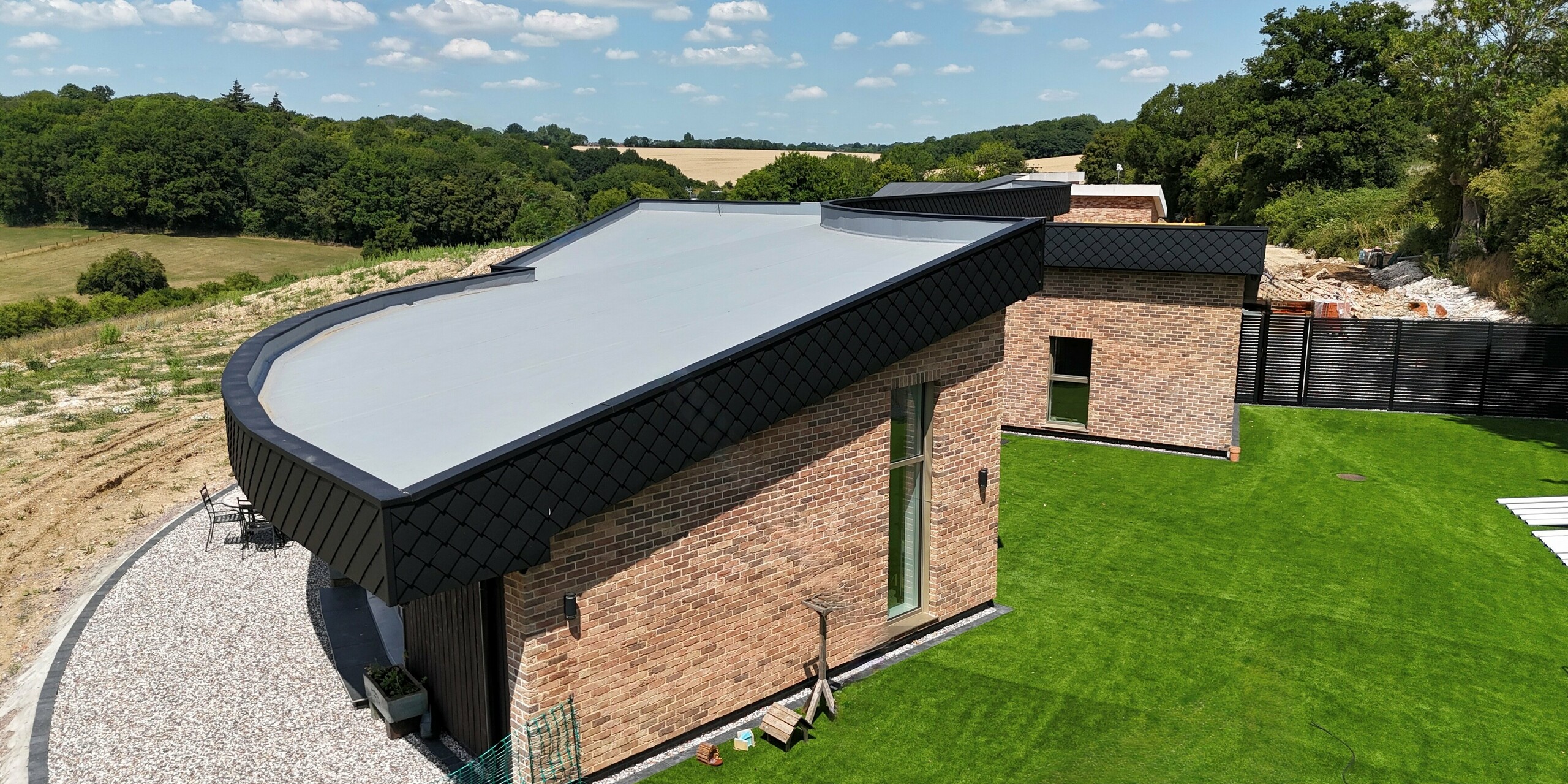 Cette maison individuelle moderne, faisant partie du projet résidentiel « Doone Brae Farm », impressionne par son design remarquable. La façade en briques se fond harmonieusement dans les losanges de façade PREFA 20 x 20 de couleur anthracite. Cette maison écologique est nichée dans un écrin de verdure.