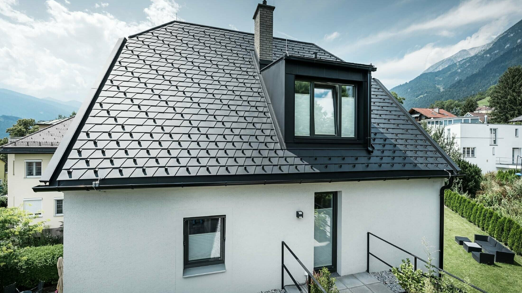 Kleines Einfamilienhaus mit einer Dachgaube. Das Dach wurde mit PREFA Dachschindeln in der Farbe P.10 Schwarz gedeckt. 