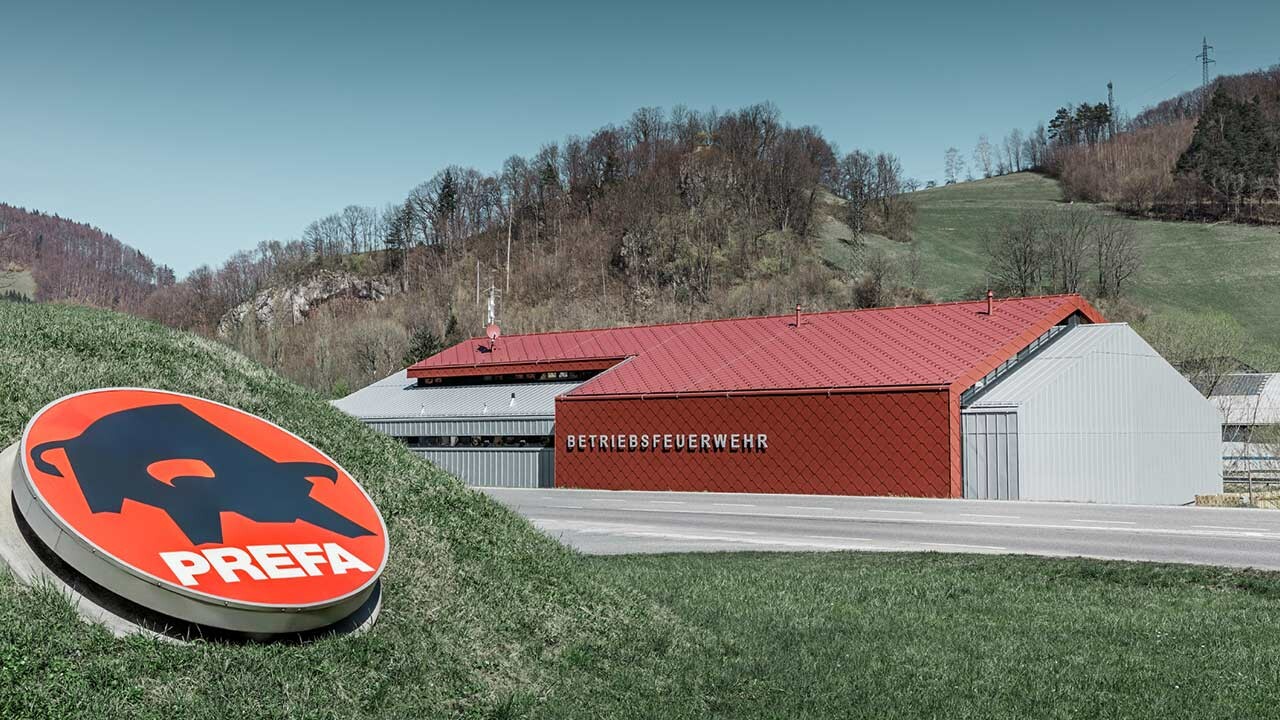 neue Betriebsfeuerwehr in Marktl, Lilienfeld, mit der roten Dach- und Wandraute 44x44 von PREFA mit dem PREFA Logo im Vordergrund, mit silbermetallic Alufassade am Seitenteil