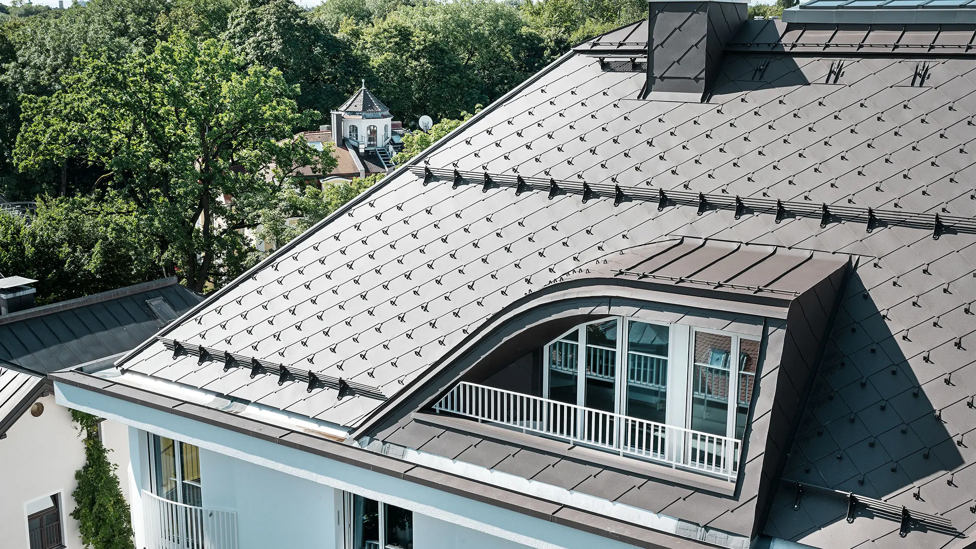 Casa plurifamiliare con scaglia PREFA 44 × 44 marrone con nasi fermaneve e sistema fermaneve