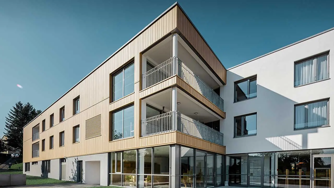 Casa di riposo con copertura piana e una facciata in doghe PREFA marrone sahara