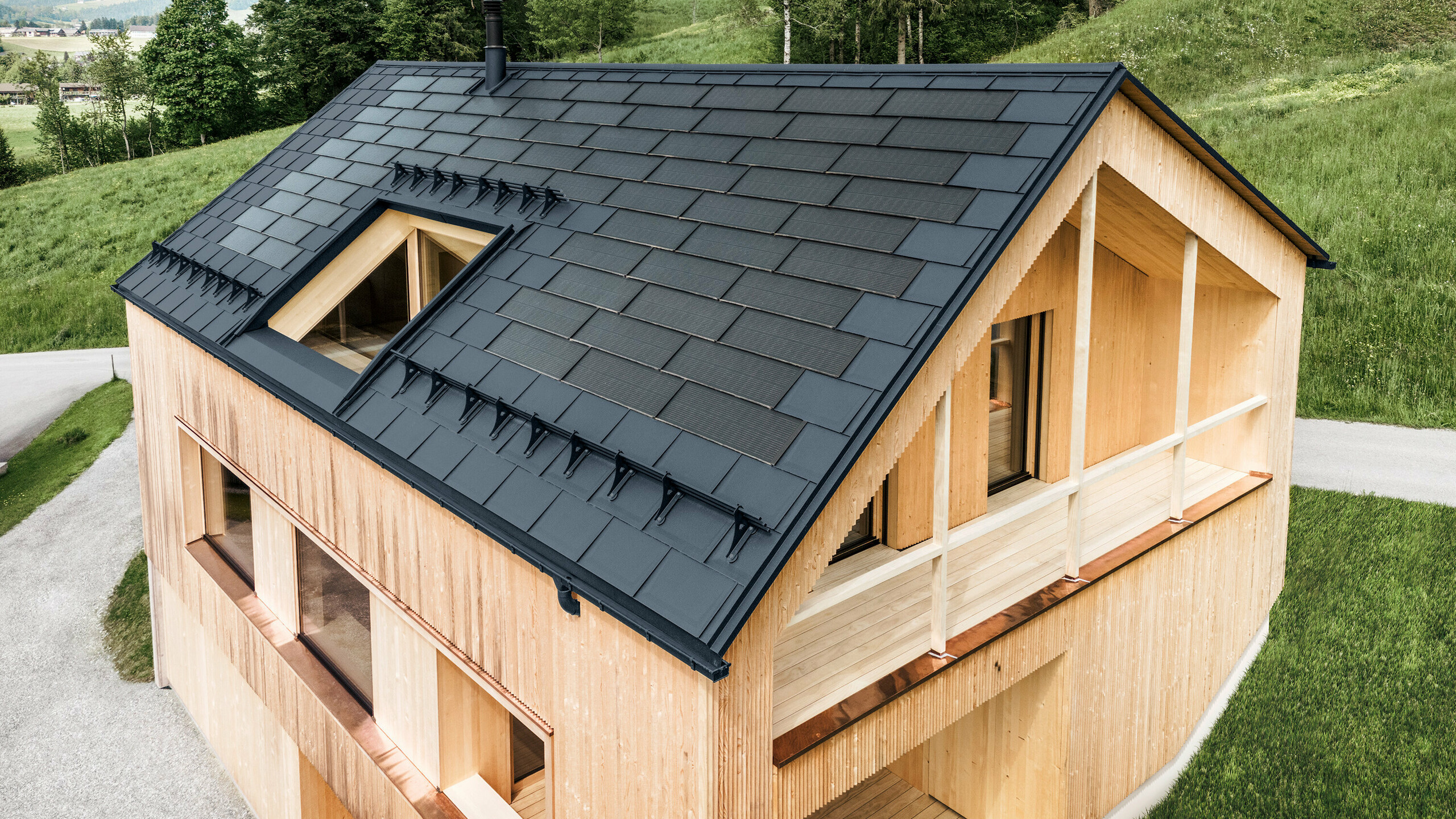 Maison individuelle dans la localité autrichienne d'Egg avec le panneau solaire de toiture PREFA et le panneau de toiture R.16 en anthracite, combinés à une façade en bois
