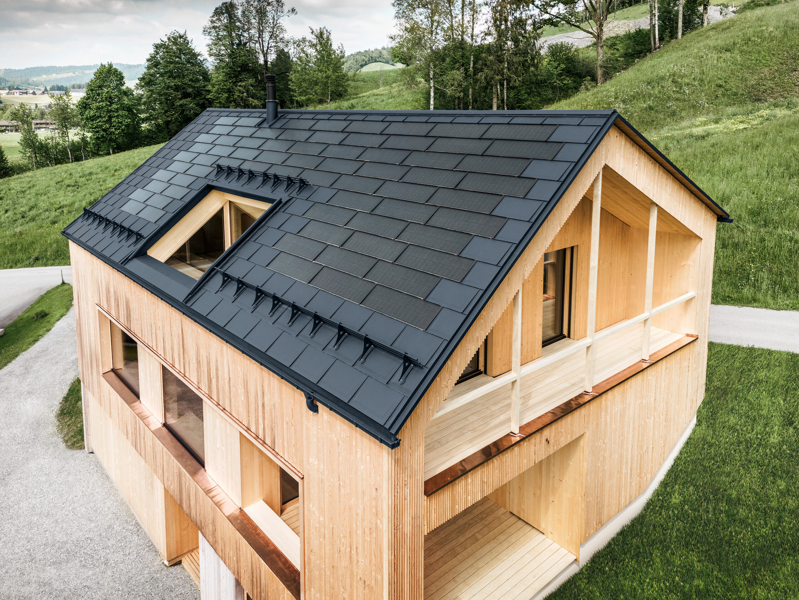 Maison individuelle dans la localité autrichienne d'Egg avec le panneau solaire de toiture PREFA et le panneau de toiture R.16 en anthracite, combinés à une façade en bois