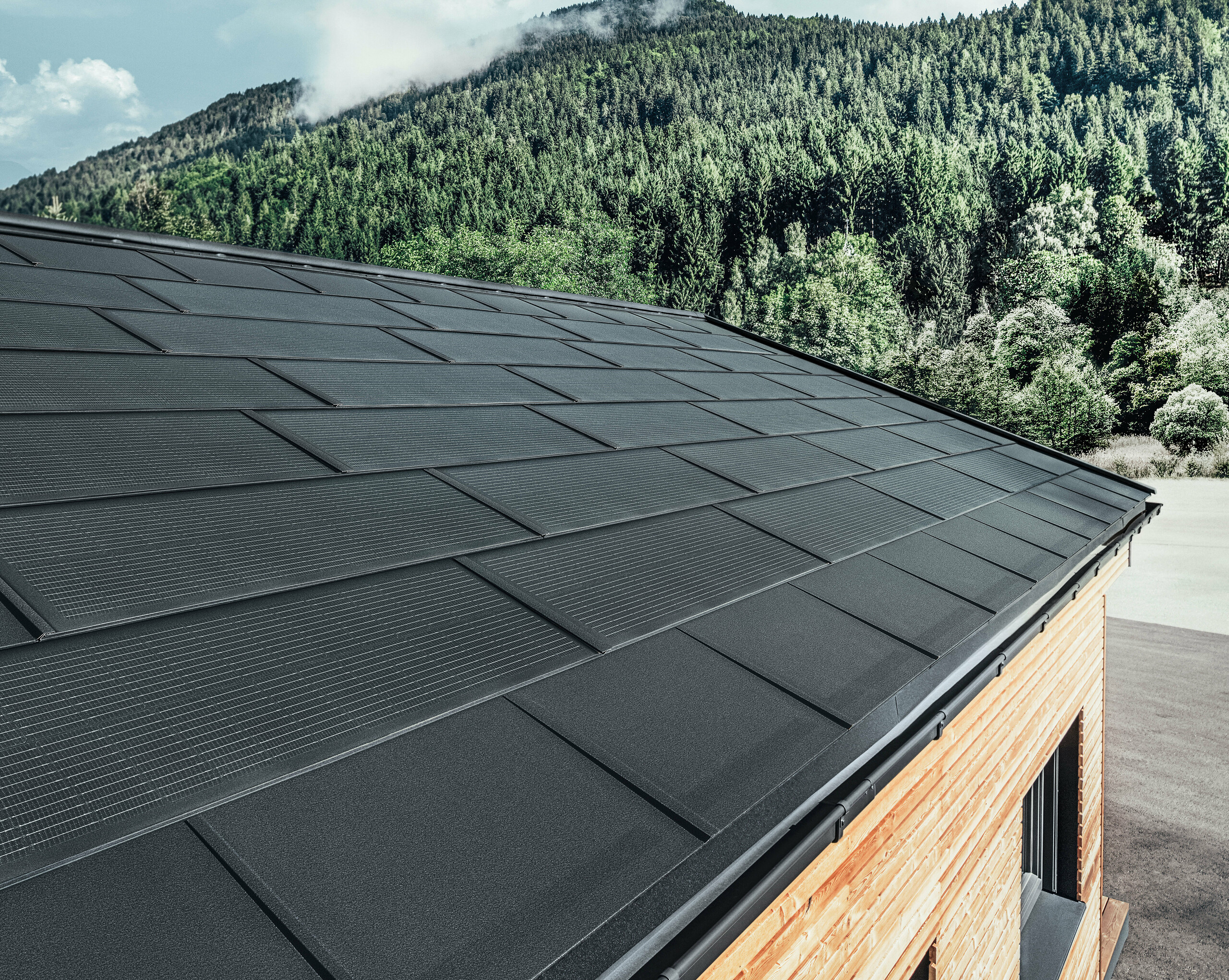 PREFA Solardachplatte in großer Ausführung kombiniert mit der Dachplatte R.16 in Schwarz, Kastenrinne und Lärchenholz-Fassade
