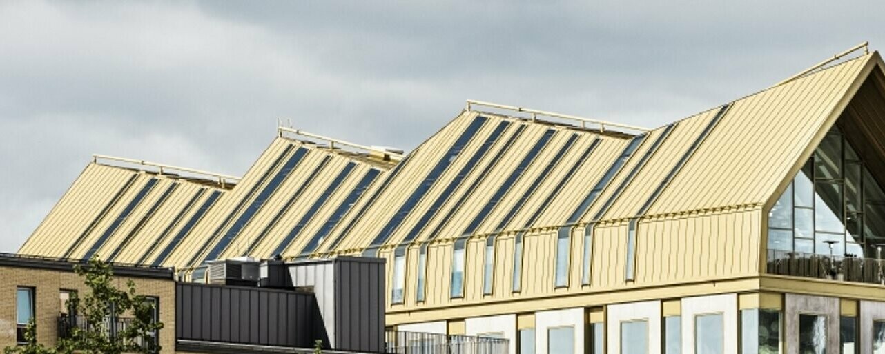 seitliche Frontansicht des Gebäudes in Malmö eingedeckt mit dem Dachsystem PREFALZ in der Sonderfarbe Jaisalmer Gold