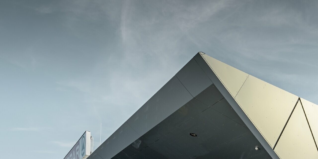 Entrée de la nouvelle filiale Eurospar de Wels habillée de panneaux de façade modernes de PREFA couleur argent doré ; selon l’angle de vue, à la lumière du soleil les panneaux composites en aluminium chatoient dans différentes couleurs.