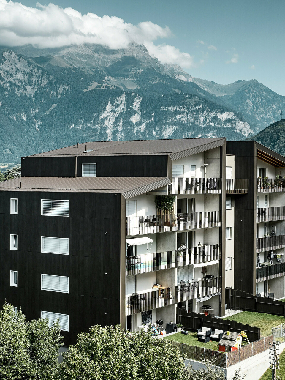 Die Fassade der Wohnhausanlage Les Dailles wurde großflächig mit dem eindrucksvollen PREFA Zackenprofil in Bronze verkleidet. Das Dach des Gebäudes wurde mit PREFALZ in Bronze eingedeckt.