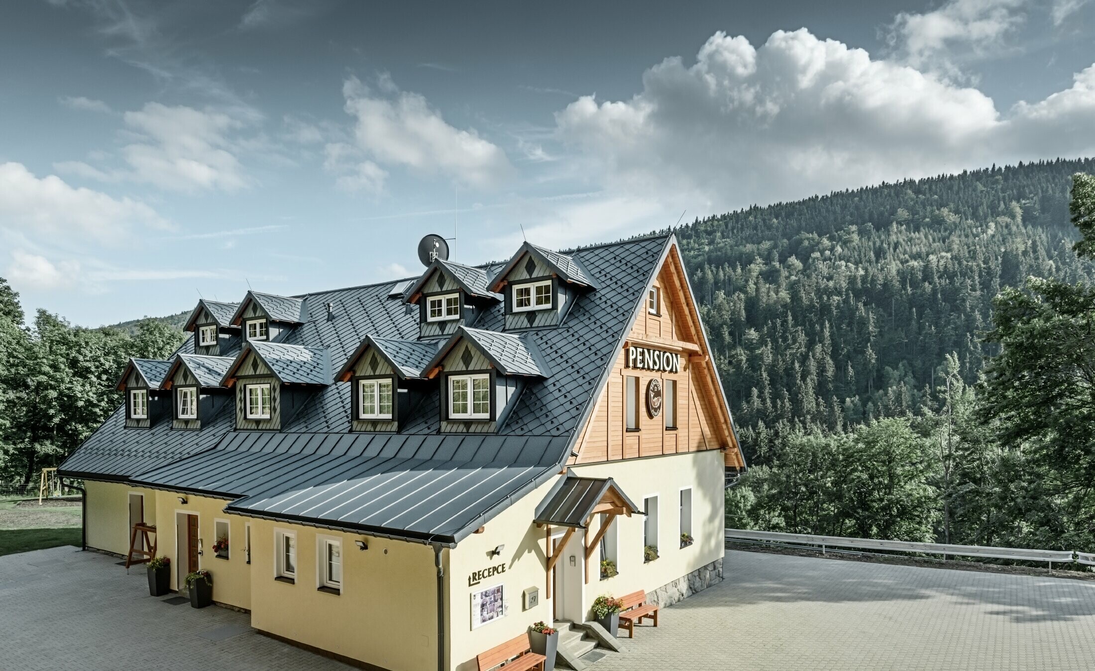 Pensione in Repubblica Ceca, con tetto inclinato e molti abbaini, rivestita con un tetto in alluminio di PREFA, tetto a scaglie sistema paraneve
