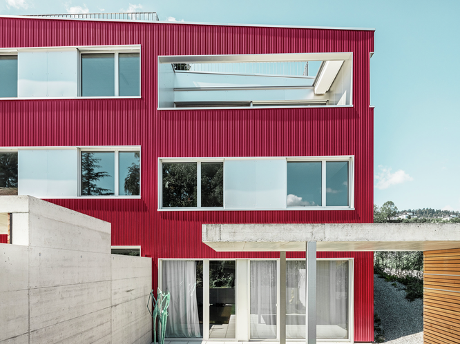 Vue de face de cet immeuble résidentiel sur le lac de Zurich en Suisse sous le soleil et un ciel bleu, revêtu de profil sinus PREFA en bordeaux