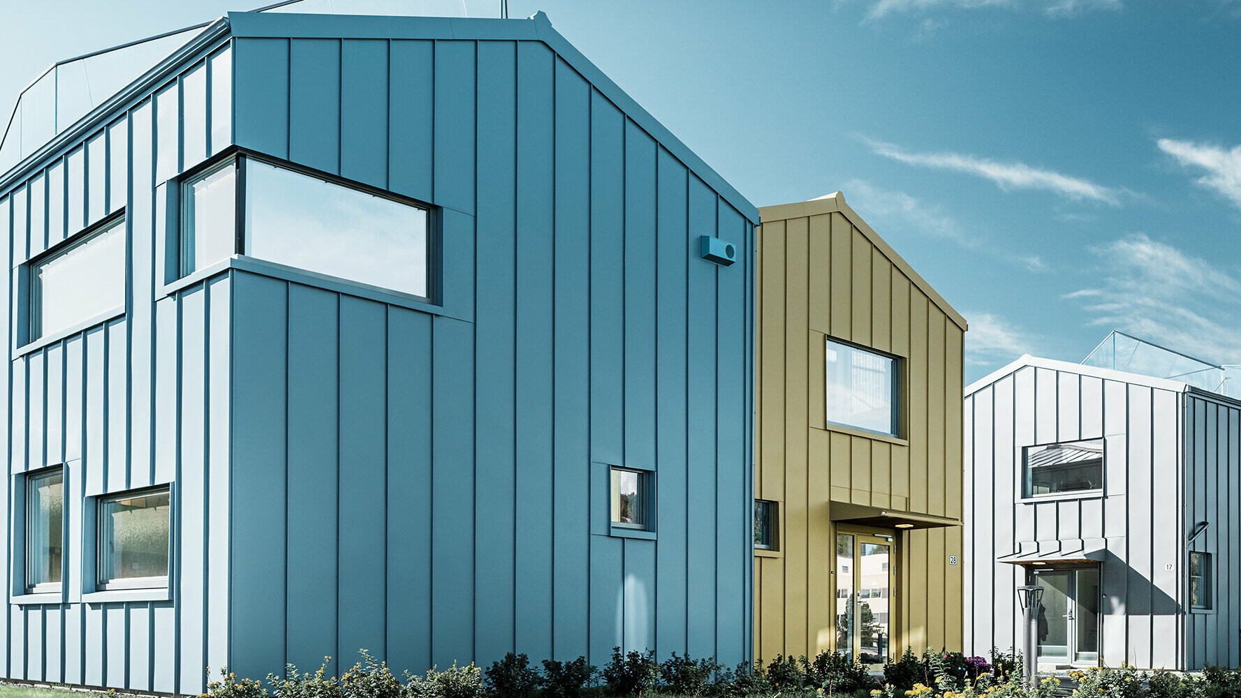 Case unifamiliari in un complesso di abitazioni con tetti e facciate in alluminio in varie colorazioni.