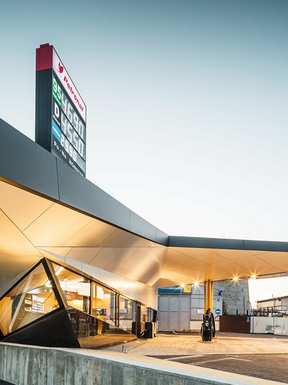 Seitlicher Blick auf die dynamische, mit Aluminium bekleidete Tankstelle von Architekt Daniel Zerzán: Etliche Dreiecke und Trapeze strukturieren die Fassade.