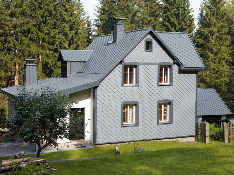 Casa unifamiliare in una zona boschiva con facciata in alluminio PREFA resistente agli agenti atmosferici in grigio chiaro.
