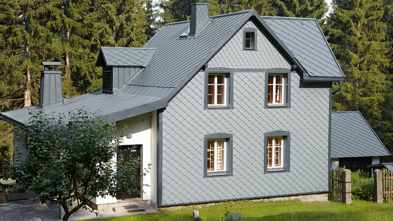 Casa unifamiliare in una zona boschiva con facciata in alluminio PREFA resistente agli agenti atmosferici in grigio chiaro.