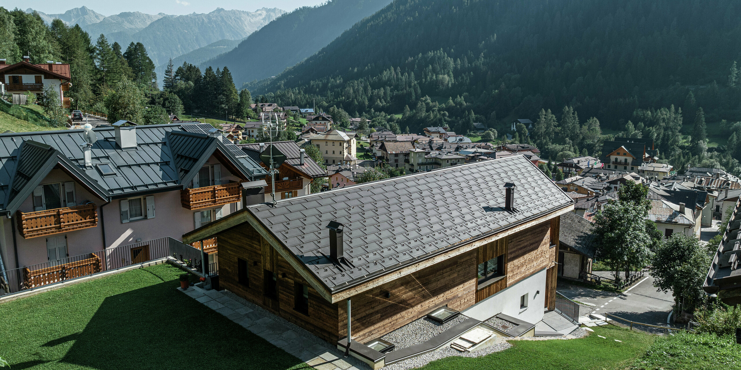 Le refuge de montagne de Cogolo, en Italie, avec sa façade en bois et son toit en aluminium PREFA de couleur P.10 brun, s'intègre parfaitement dans le paysage alpin. Le R.16 offre une protection fiable contre la neige, le vent et la pluie et garantit une longue durée de vie. Une solution durable et élégante pour les conditions météorologiques extrêmes en montagne. En arrière-plan, vous pouvez voir l'impressionnant panorama montagneux du Val di Sol.