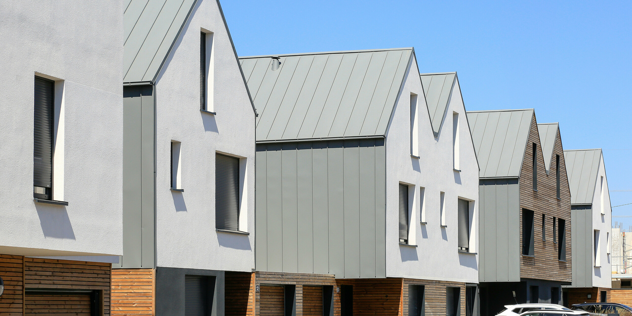 Le joint debout PREFALZ en gris souris s'étend sur les façades et les toits à pignon d'un lotissement mitoyen à Mundolsheim. Les coques uniformes du bâtiment en aluminium créent une image globale harmonieuse.