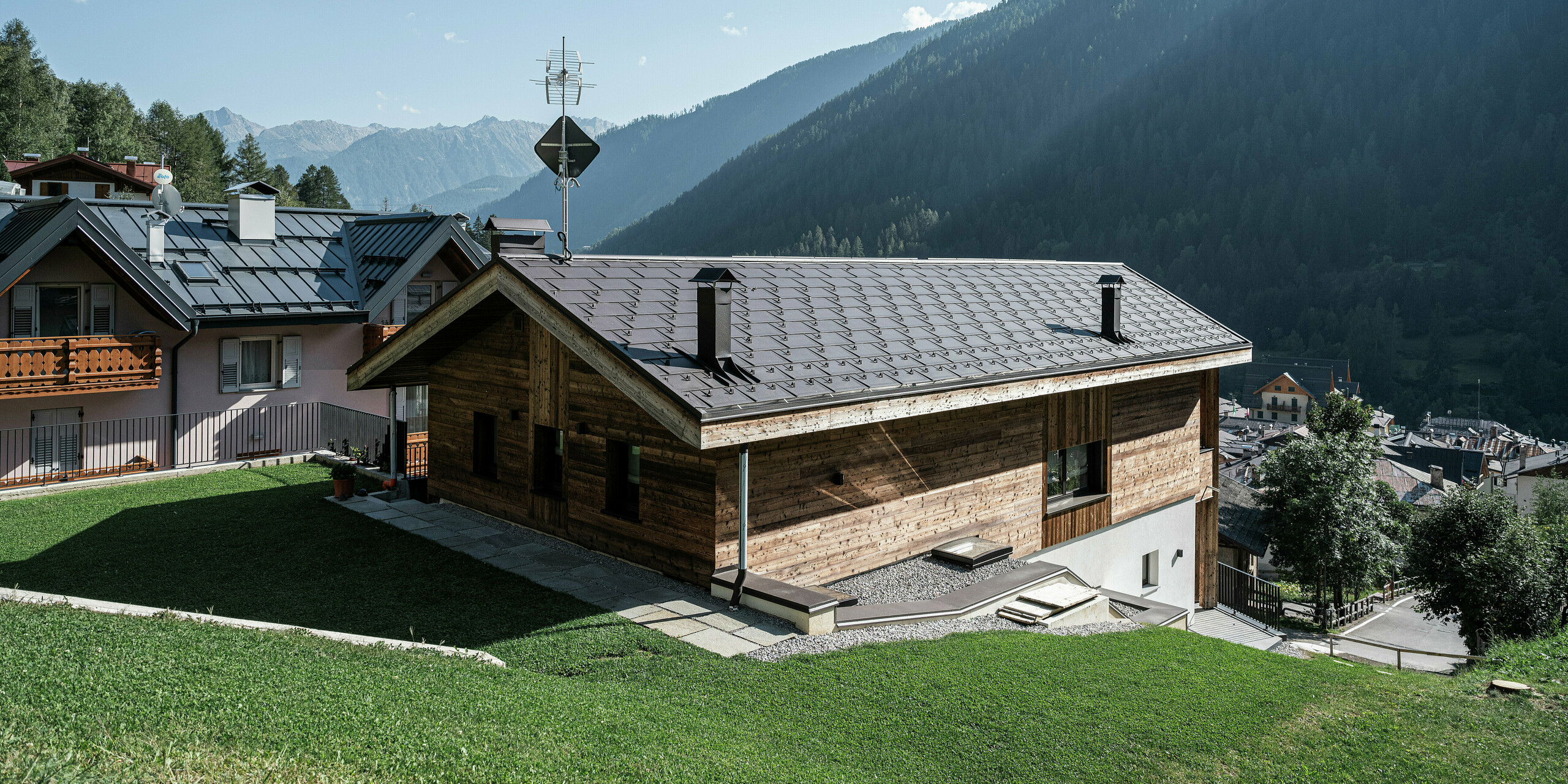 Arrière d'une maison de montagne moderne à Cogolo, dans le Val di Sol italien, avec des R.16 PREFA durables en P.10 brun. Le toit robuste en aluminium s'intègre parfaitement dans le paysage alpin et protège de manière fiable le bâtiment de la neige, du vent et des intempéries. Des lignes claires et une capacité de charge maximale font de ce toit la solution idéale pour les régions de haute altitude.