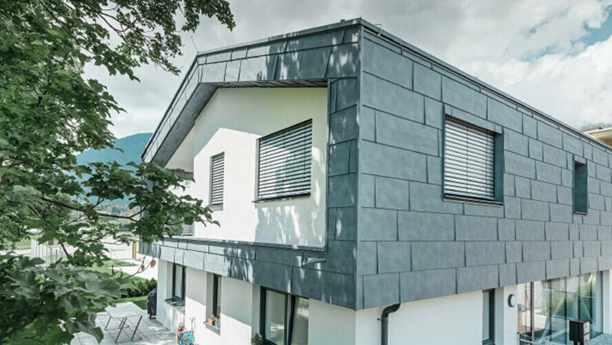 Erster Stock eines modernen Wohnhauses verkleidet mit PREFA Aluminum Fassadenpaneelen FX.12 in der Farbe Steingrau.