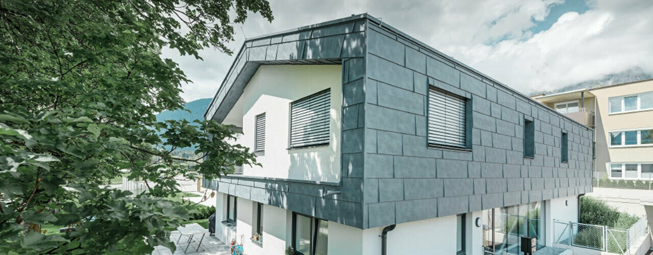 Premier étage d’un bâtiment d’habitation moderne revêtu de panneaux de façade FX.12 PREFA en aluminium de couleur gris pierre.