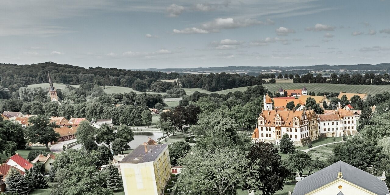 Prise de vue aérienne des écuries de Basedow ; rénové, le château de style renaissance présente lui aussi une nouvelle toiture réalisée avec le bardeau de toiture PREFA couleur anthracite.