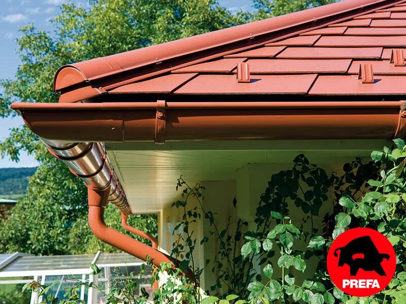 Casa monofamiliare con tetto a padiglione e abbaino rivestita con scandole in alluminio PREFA con estetica di laterizio nel colore rosso cotto