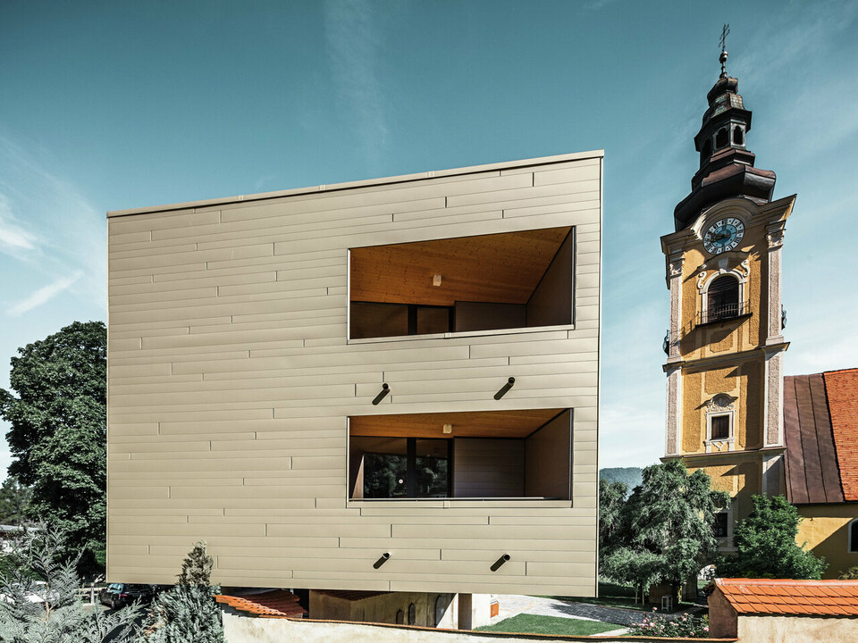 Vue de côté de la résidence universitaire de Leoben. En fond, on aperçoit une église.