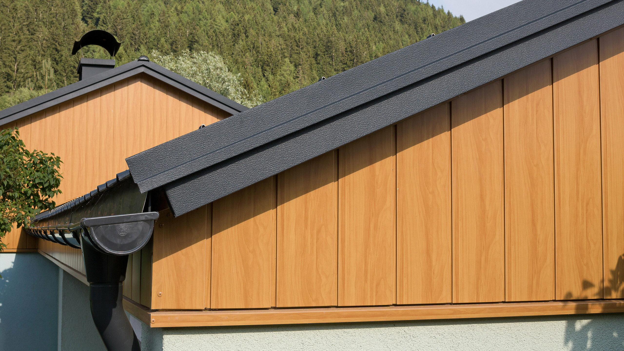 Giebelverkleidung mit den Alu Sidings von PREFA in Eiche natur senkrecht montiert mit einer PREFA Dachrinne in Anthrazit.