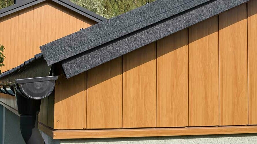 Revêtement de pignon avec les Sidings en aluminium de PREFA couleur chêne naturel montés à la verticale avec une gouttière PREFA anthracite.