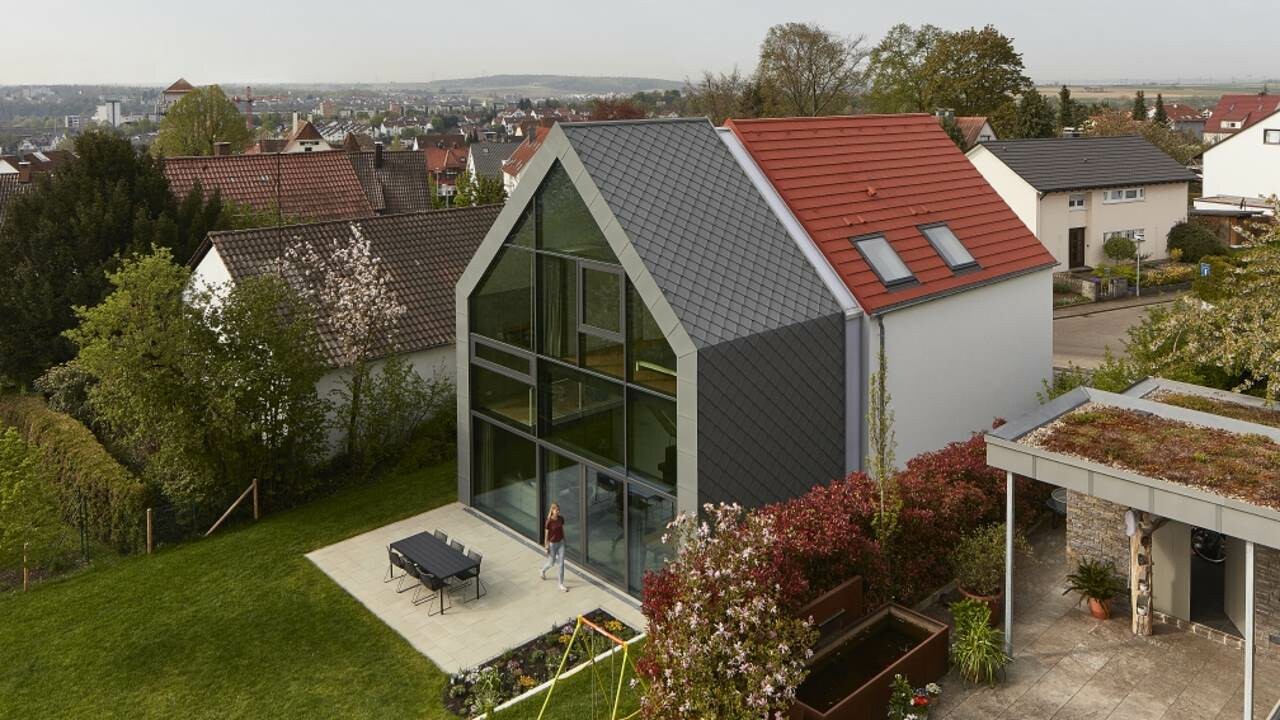 seitliche Ansicht des Haus J in Stuttgart (Deutschland). Im Hintergrund erkennt man einen bewölkten Himmel. Das Haus J wurde mit der Dachraute 29 × 29 in der Farbe P.10 Hellgrau verkleidet.