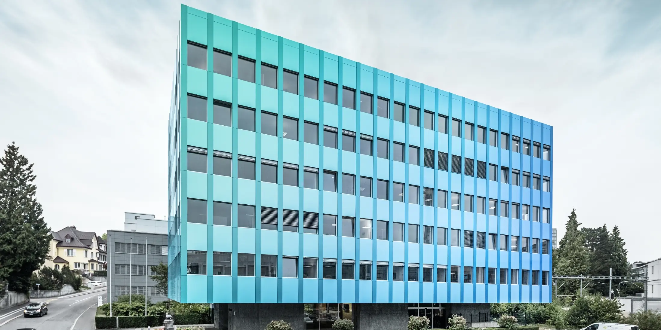 Vista laterale della Wielandhaus ad Aarau; la facciata è rivestita con pannelli compositi in alluminio PREFABOND di PREFA, che grazie allo speciale processo di rivestimento brillano di riflessi blu-verdi.