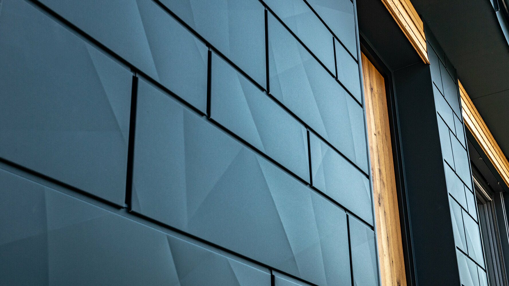 Pannello per facciata PREFA con effetto ottico irregolare; Doga.X in alluminio PREFA in antracite combinato con facciata in legno.
