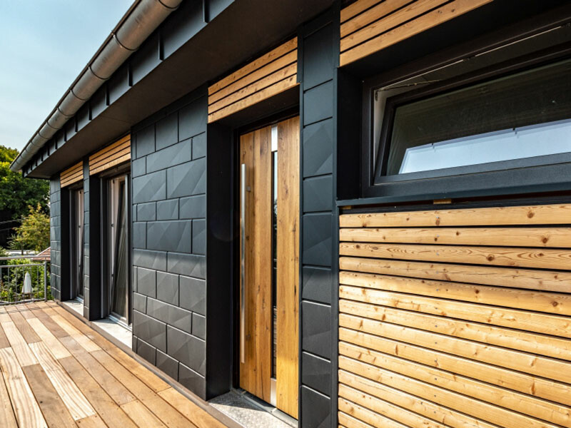 Maison individuelle moderne revêtue de jolis panneaux de façade Siding.X PREFA couleur anthracite et d’éléments en bois.