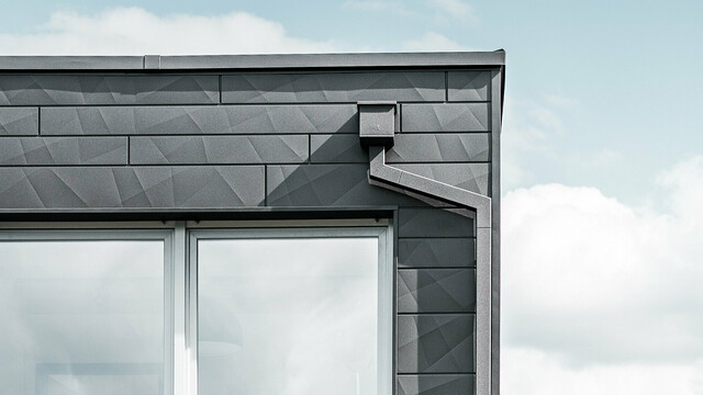 Gebäudeabschnitt eines modernen Einfamilienhauses mit Flachdach, die Entwässerung erfolgt mit dem hochwertigen PREFA Quadratrohr in Schwarz auf einer PREFA Siding.X Fassade.