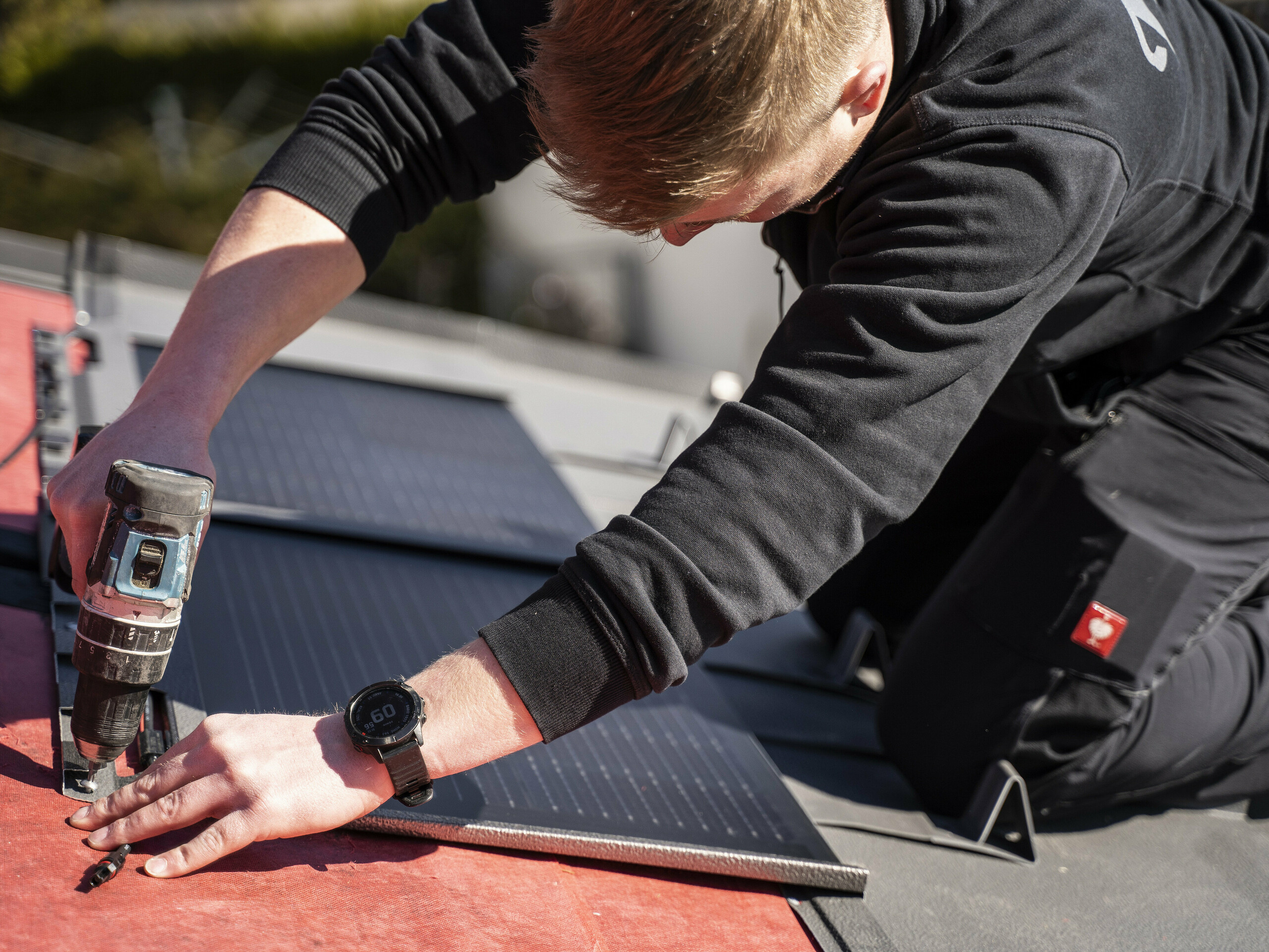 Un dipendente PREFA che posa la tegola fotovoltaica sul tetto.