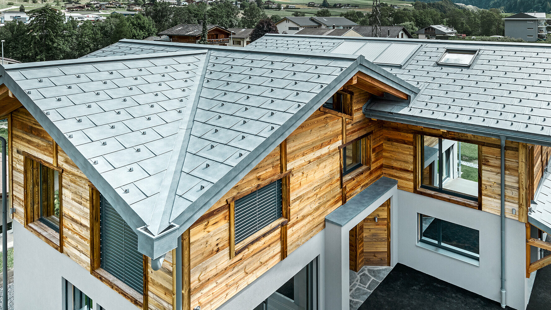  Chalet avec une couverture de toit PREFA couleur P.10 gris pierre, combinée avec une façade en bois
