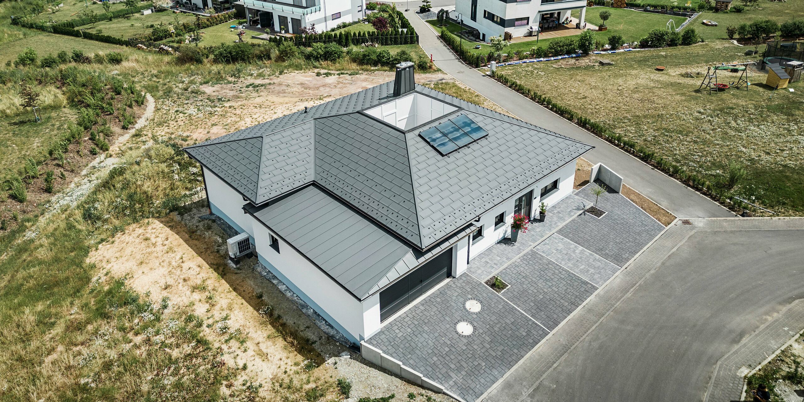 R.16 PREFA et joint debout PREFALZ ainsi que tuyau de descente et gouttière suspendue en P.10 gris sombre sur le toit d'un bungalow. 