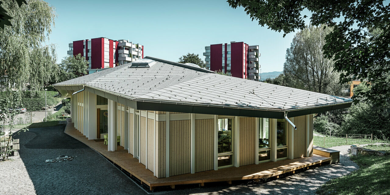 Jardin d’enfants de plain-pied avec panneaux de façade verticaux et toiture en aluminium de PREFA (losange de toiture) couleur gris souris