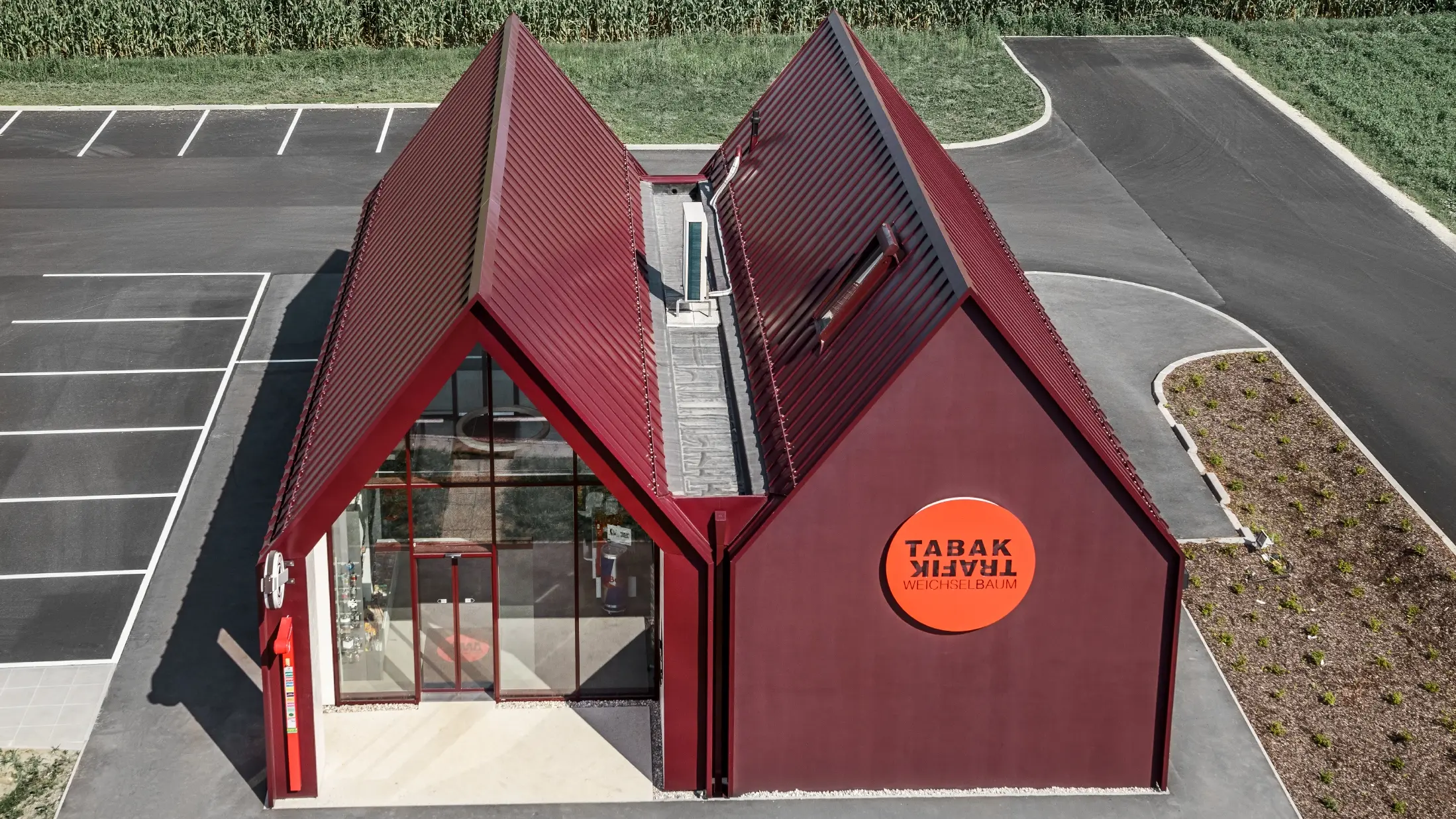 moderne Trafik mit Satteldach und ohne Dachvorsprung und einer Aluminiumhülle von PREFA als Stehfalz- und Winkelstehfalz in der Sonderfarbe schwarzrot ausgeführt