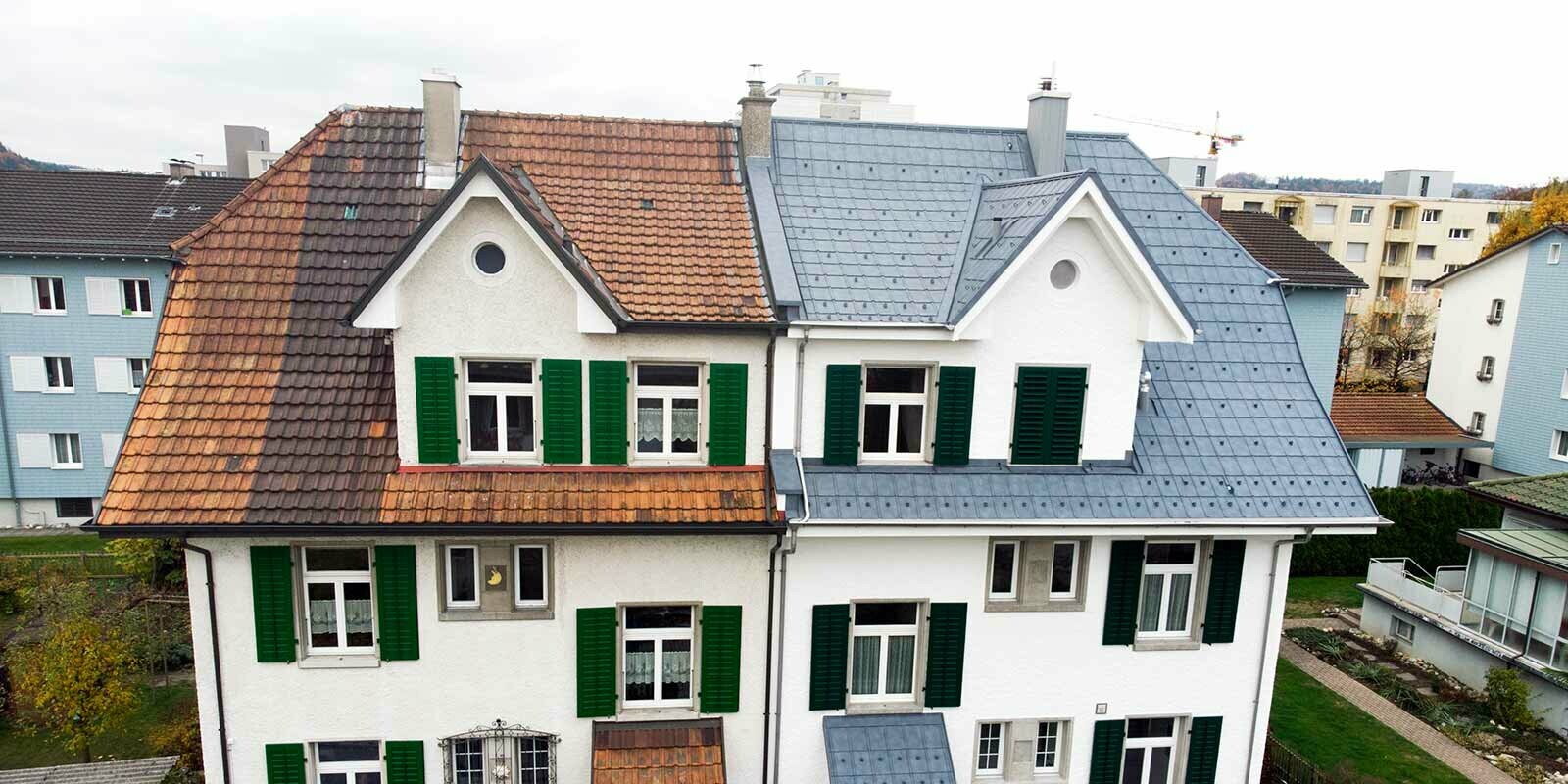 Moitié de maison jumelée en Suisse. La partie gauche du bâtiment n’a pas encore été rénovée et est encore recouverte de tuiles sales. La partie droite du bâtiment a été recouverte à l’aide de tuiles PREFA couleur gris pierre.